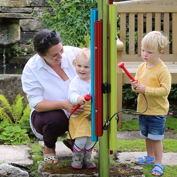 a little boy and girl playing a music chime post in a garden