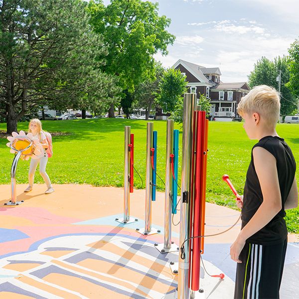 a teenage boy in a black t shirt playing outdoor musical chimes in rainbow colors