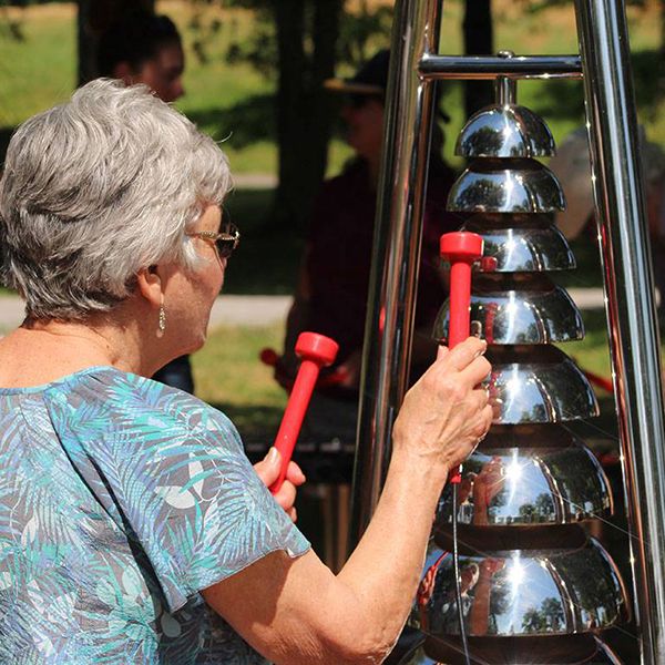 an older lady playing an outdoor bell lyre in the belleville rotary musical garden