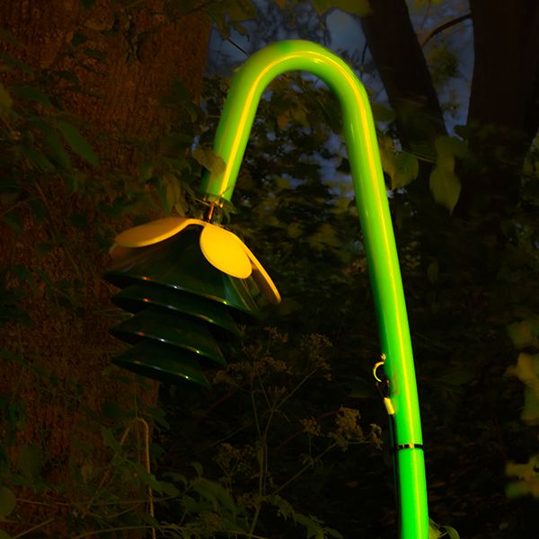 A Harmony Bell outdoor musical instrument shaped like a flower lit up in green lights