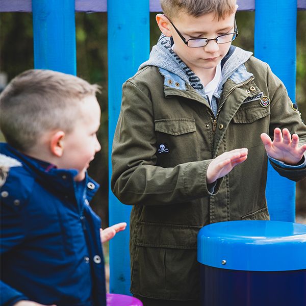 two boys playing colourful outdoor conga drums in the musical maze at national forest adventure farm