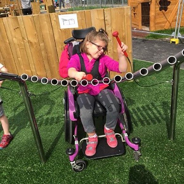 little girl in a wheelchair playing a large outdoor musical instrument in the new playground at Greystones Co Wicklow Ireland