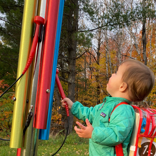 young boy wearing a rucksack playing a colorful outdoor musical chime in Bethlehem public library