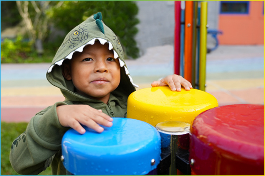 Young boy experimenting with untuned percussion instruments outdoors