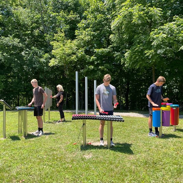 Family of young adults playing outdoor musical instruments in a park