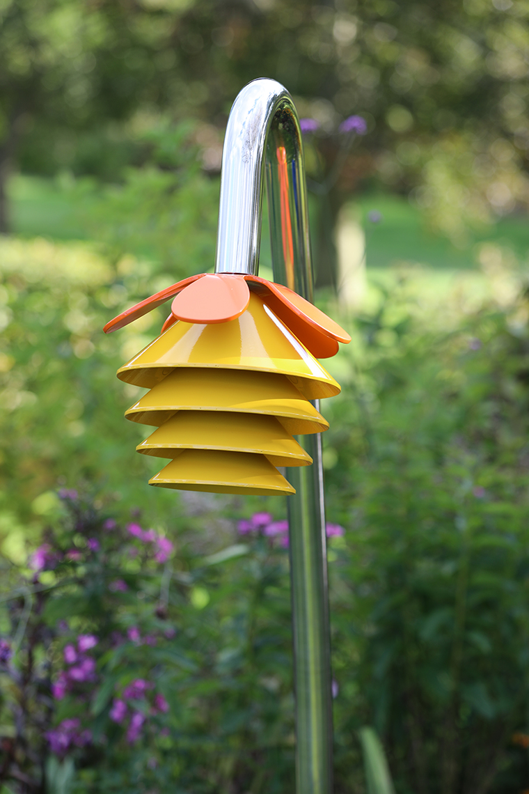 An outdoor musical flower comprising four yellow bells and a petal on a stainless steel 'stalk' for playgrounds and sensory gardens