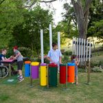 four children playing a group of outdoor musical instruments in a playground 