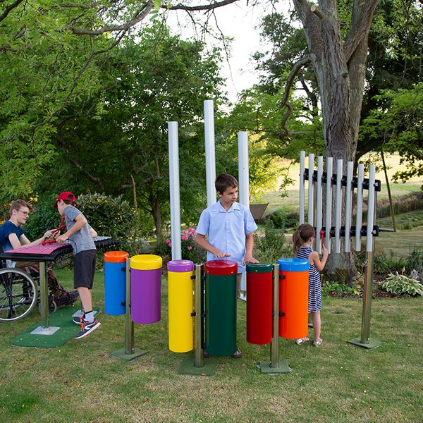 four children playing a group of outdoor musical instruments in a playground 