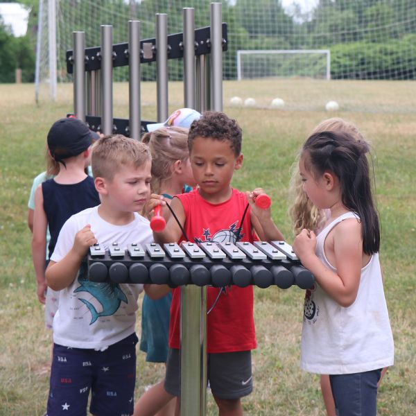 Children playing outdoor musical instruments in the grounds of Camp Henry