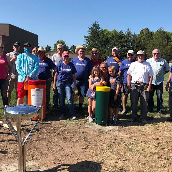 Hastings Noon Kiwanis team standing next to a recently completed outdoor musical playground in the Hawthorne Elementary School Playground