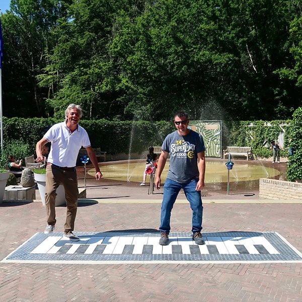 two men jumping on a large mechanical floor piano at Drielandenpunt in th Netherlands