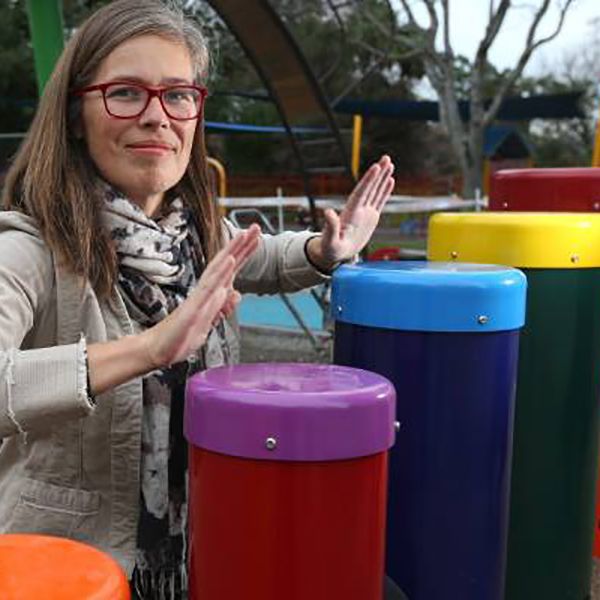 music therapist playing on outdoor playground drums in a new inclusive playground