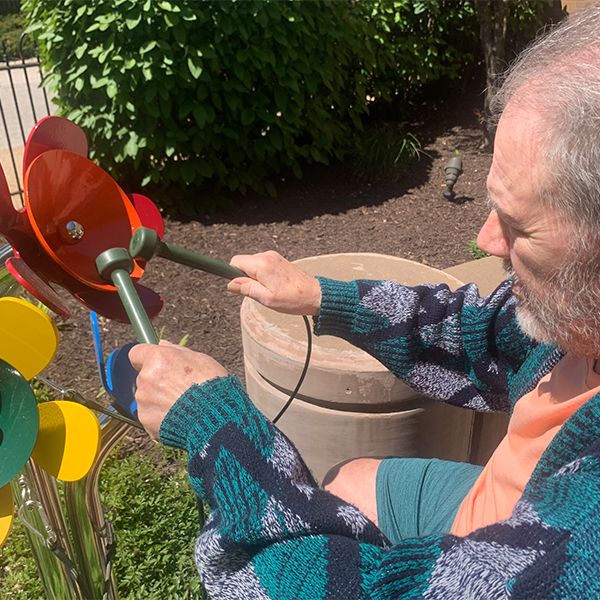 senior male in a wheelchair playing outdoor musical flowers at the laclede groves senior living facility