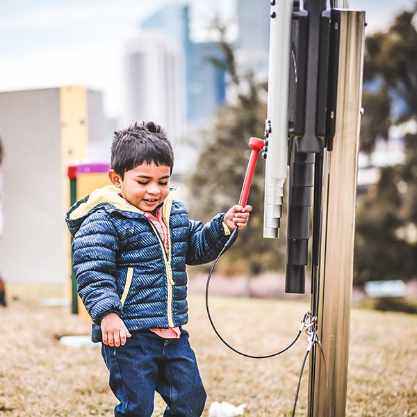 Young boy playing on an outdoor cherub xylophone at the Leonel Castillo Community Center 