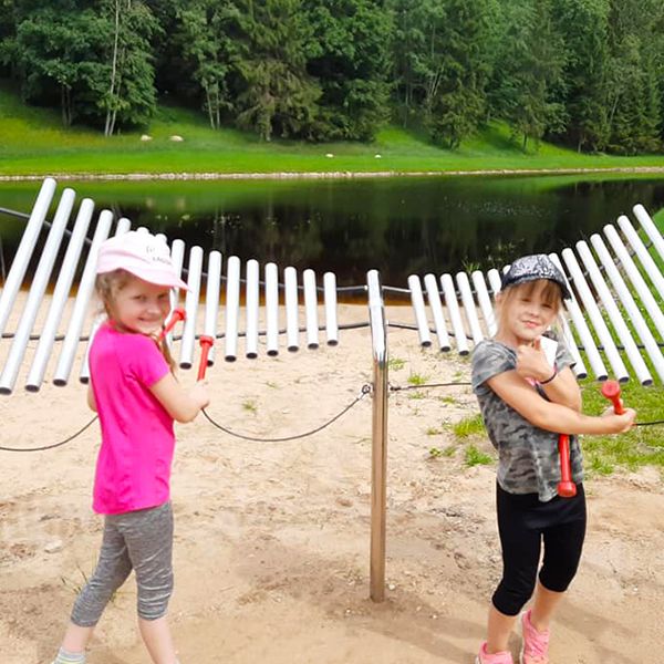 Children playing the outdoor musical instruments in the new playground at Sirvetos Regional Park in Lithuania