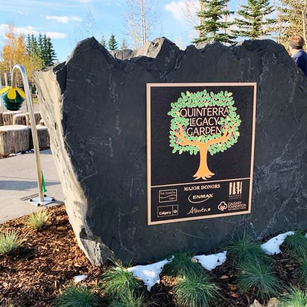 large granite boulder with a sign welcoming visitors to the Quinterra Legacy Musical Garden in Calgary