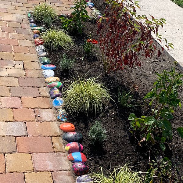 painted pebbles surrounding a memorial music sensory garden in a school playground 