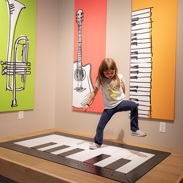 a young girl jumping on an interactive floor piano