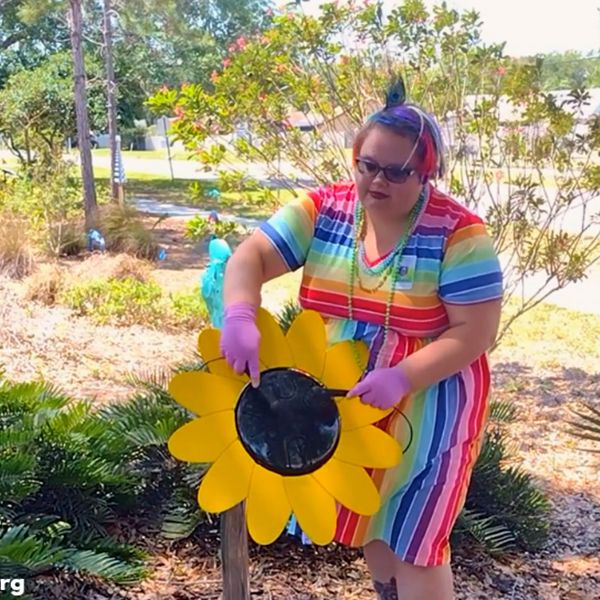 a lady playing a large outdoor drum shaped like a sunflower