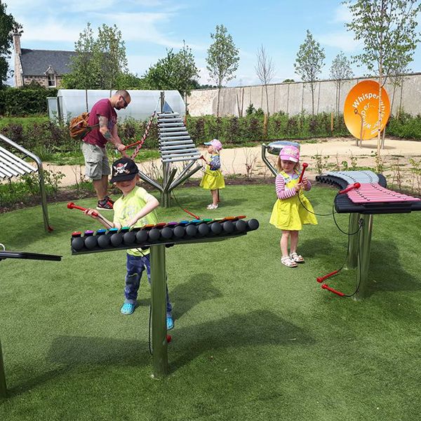 a family playing on the collection of outdoor musical instruments in the playful garden in Brodie Castle, National Trust Scotland