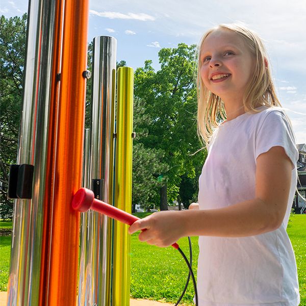 a young blonde girl playing outdoor musical chimes in rainbow colors in hamilton park fond du lac