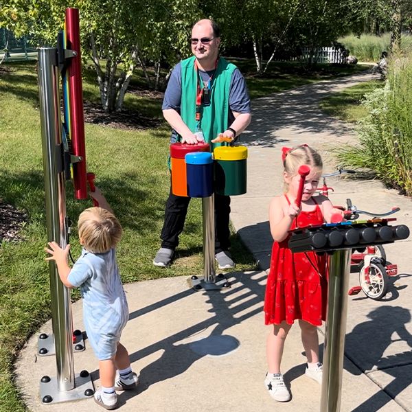 a man and three children playing outdoor musical instruments in a museum garden