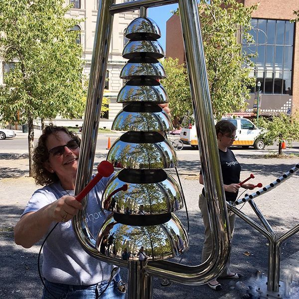 lady  playing a large musical bell tree in the street