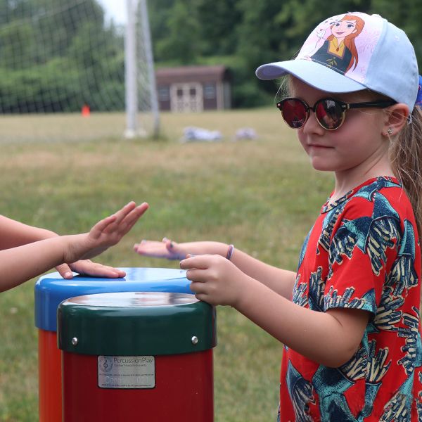 girl playing outdoor musical drum in the new musical playground at camp henry