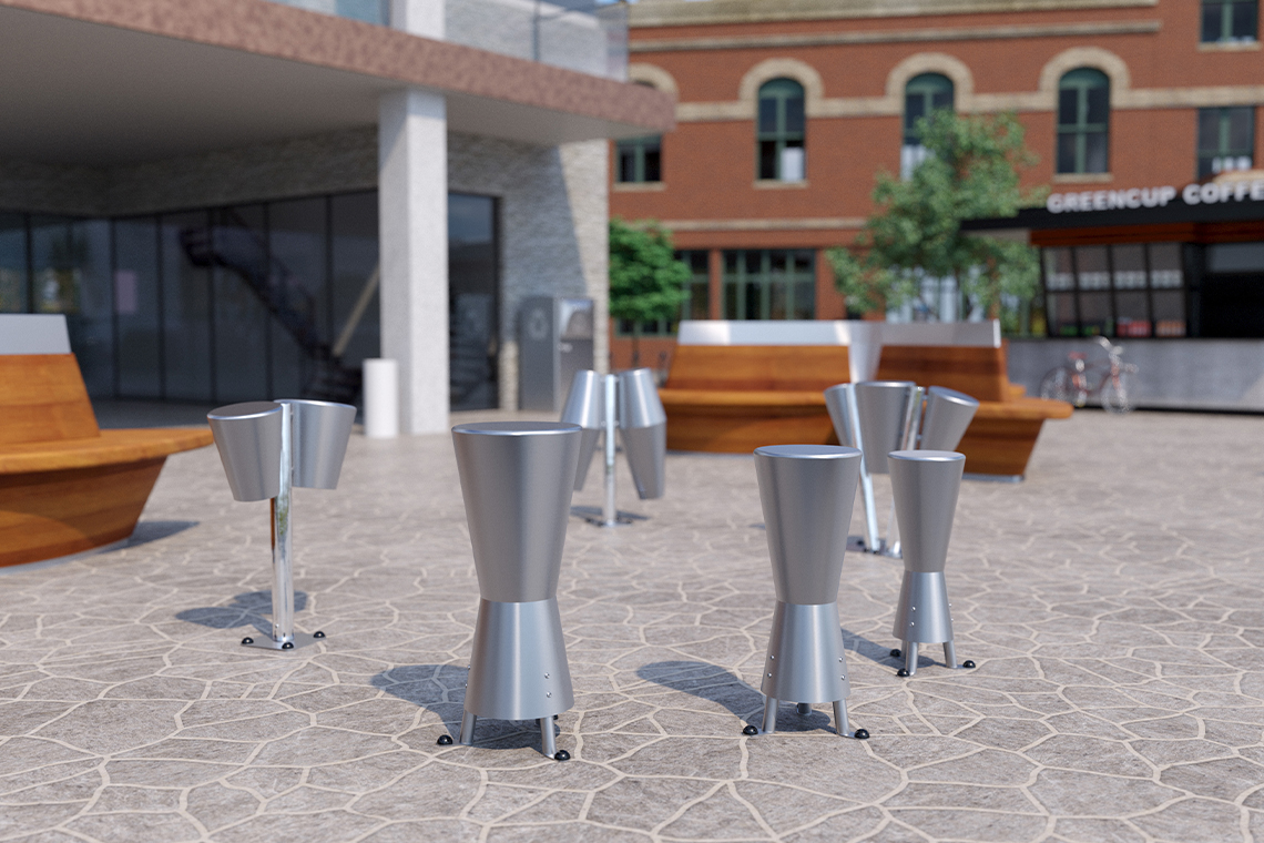 A modern outdoor plaza with a selection of stainless steel outdoor drums on a patterned stone floor. Background includes a brick building and a caf&eacute;, creating a lively urban setting.