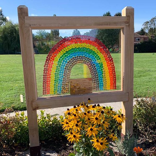 The rainbow sign outside the entrance to Henry's Memorial Musical Garden in a school playground