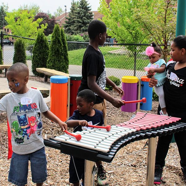 a black family playing on the outdoor musical instruments in the garden of the children's healing center