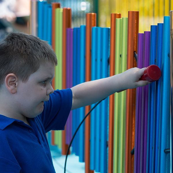 boys with special needs playing rainbow coloured chimes outdoors