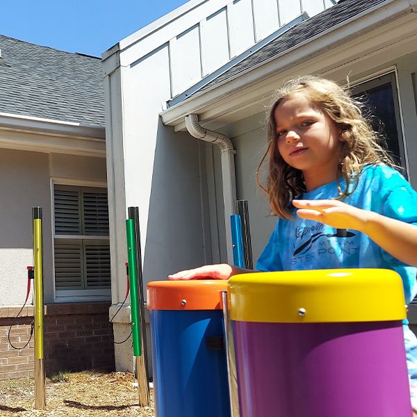 a young girl playing colorful outdoor conga drums