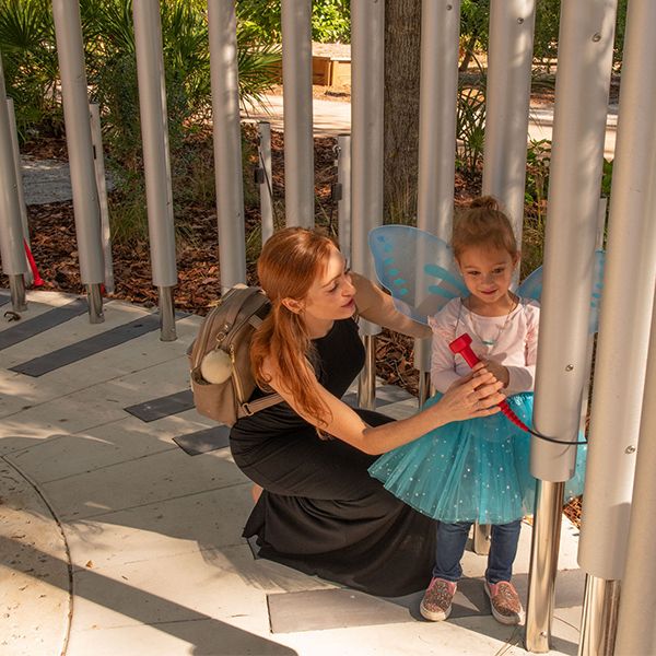 a little girl dressed as a butterfly playing on the outdoor chimes in the Florida botanical gardens