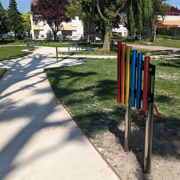 a colourful set of outdoor chimes on stainless steel posts installed on a pathway