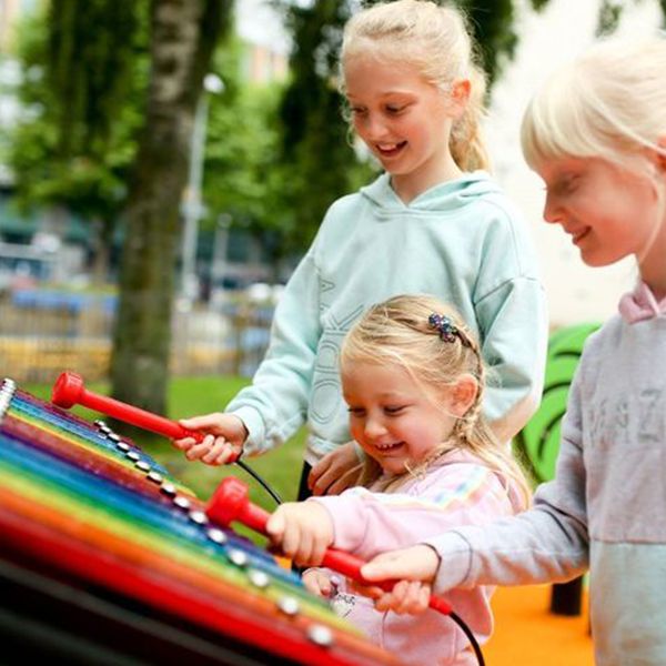 three blond girls playing the rainbow xylophone in the  inclusive music park cathedral gardens, Belfast, Northern Ireland