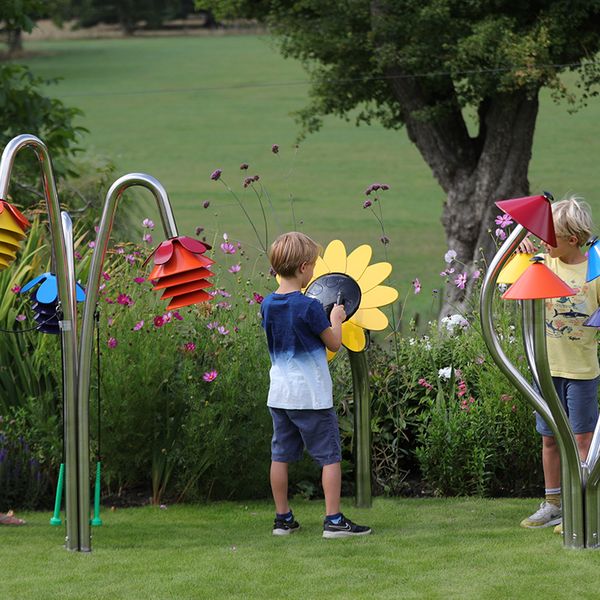three outdoor musical instruments inspired by nature being played by a mother and two sons