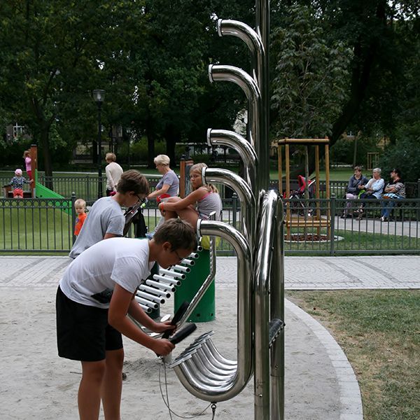 boy in a park playing outdoor slap tubes with other outdoor instruments in the background