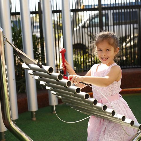 Young girl playing a silver xylophone in a playground