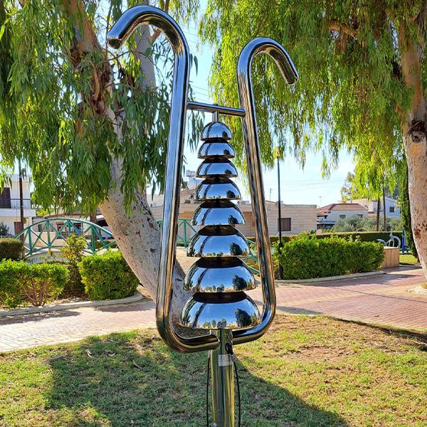 a silver outdoor musical instrument with decreasing size bells with a frame in the shape of a lyre