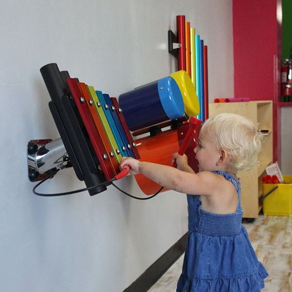 small blonde little girl hitting the rainbow coloured wall xylophone in the Building For Kids Children's Museum