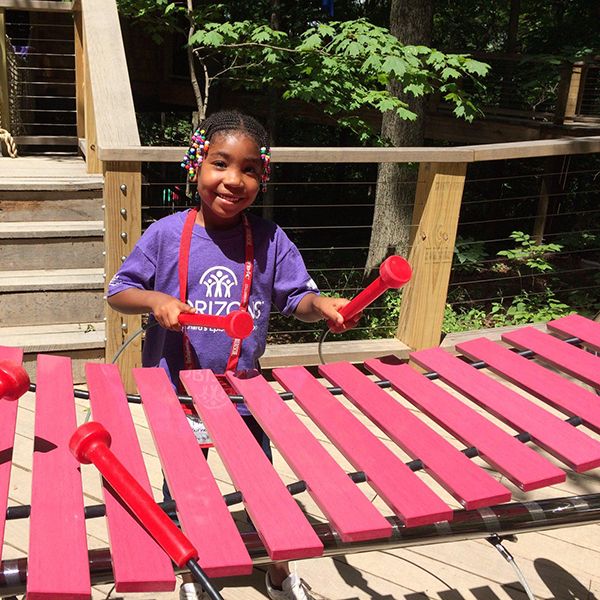 little black girl playing the marimba outdoor musical instrument at the Treetop Outpost at Conner Prairie History museum