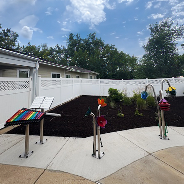 outdoor musical instruments including a xylophone with rainbow notes and musical flowers in a senior living garden