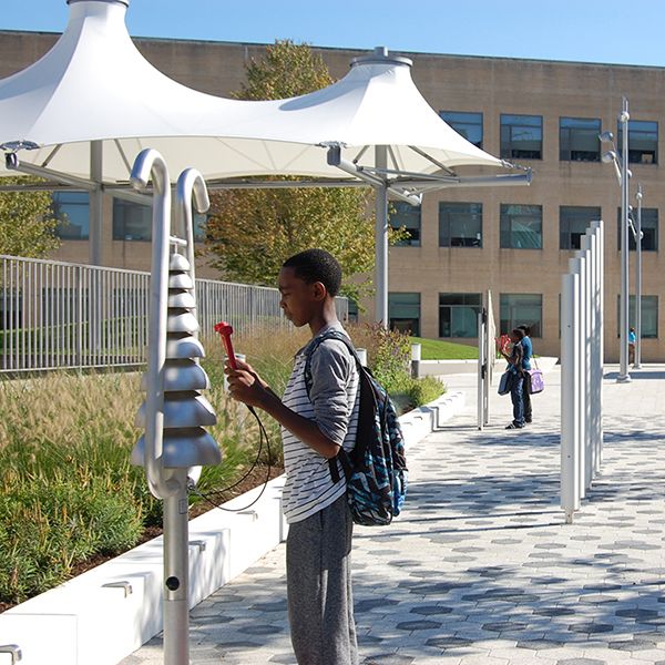 Young man playing on the silver bell lyre bell tree musical instrument on the plaza outside White Plains Public Library NY 