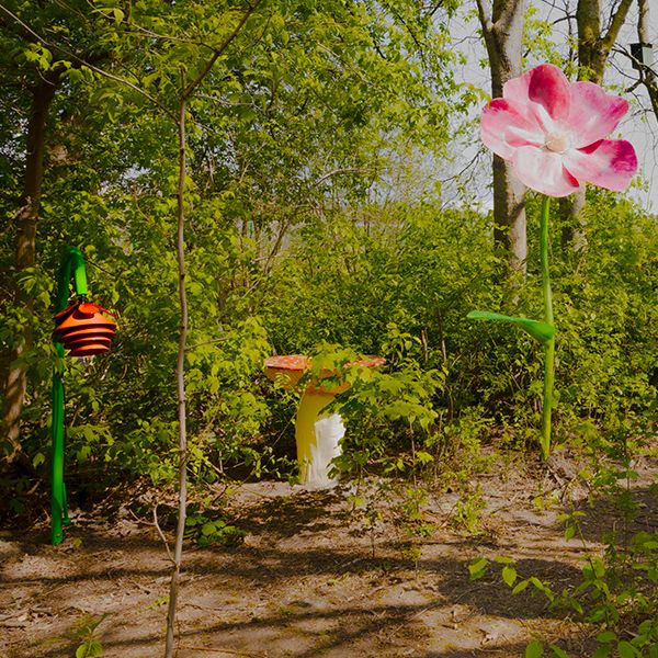 A Harmony Bell outdoor musical instrument shaped like a flower among a flower sculpture and toadstool