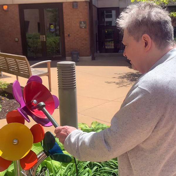 senior male playing outdoor musical flowers at the laclede groves senior living facility