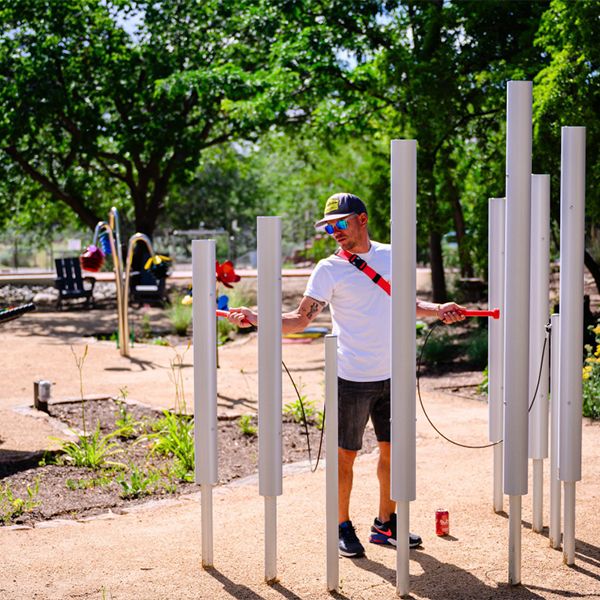 a man playing large silver tubular bells in a music playground