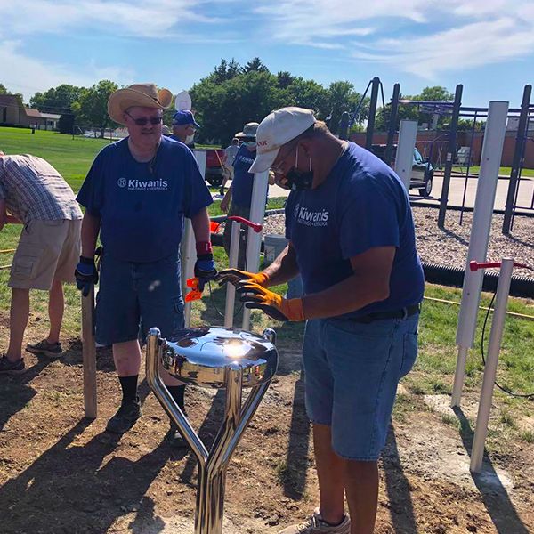 three men from Hastings Noon Kiwanis team installing outdoor musical instruments in the Alcott Elementary School Playgound