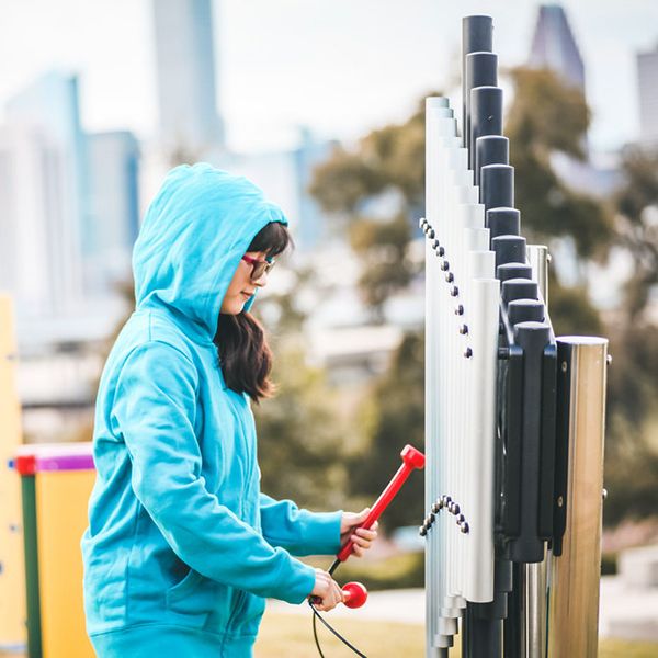 a young girl playing on the outdoor cherub xylophone at the Leonel Castillo Community Center 