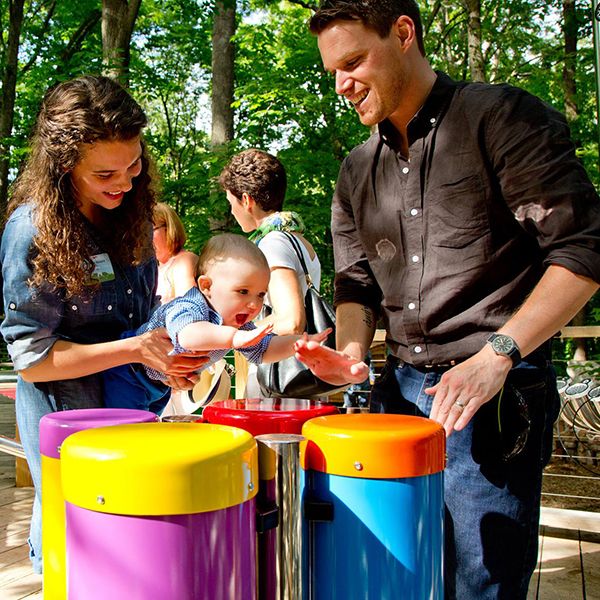 family playing the conga drums outdoor musical instruments at the Treetop Outpost at Conner Prairie History museum